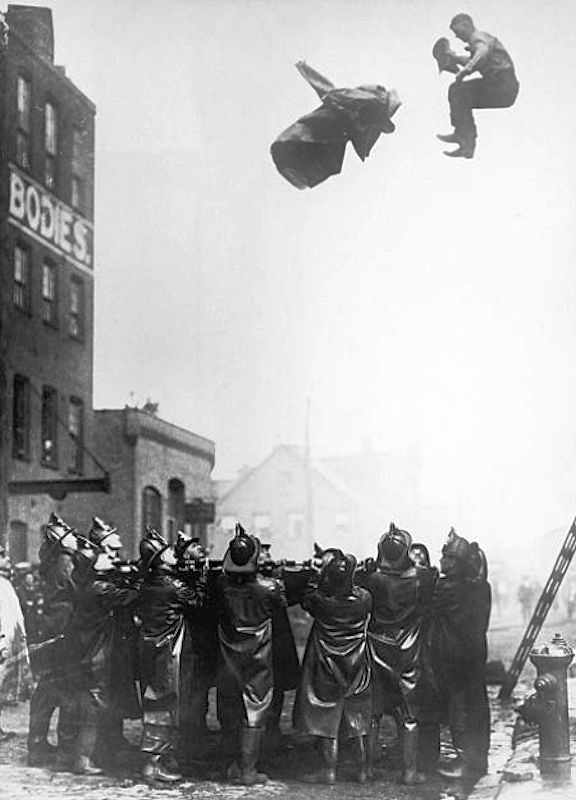 A fireman trapped in the upper floor of a burning building leaps onto a safety net held by his colleagues in Newark, New Jersey, circa 1925. He has thrown his heavy coat out in front of him. 

Photo by FPG/Hulton Archive
